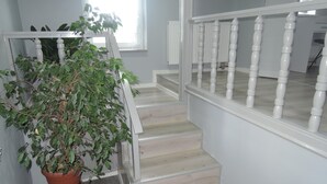 Un escalier avec des balustrades blanches et un pot de fleurs à sa base.