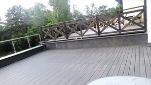 Um deck de madeira com grade, rodeado por árvores.