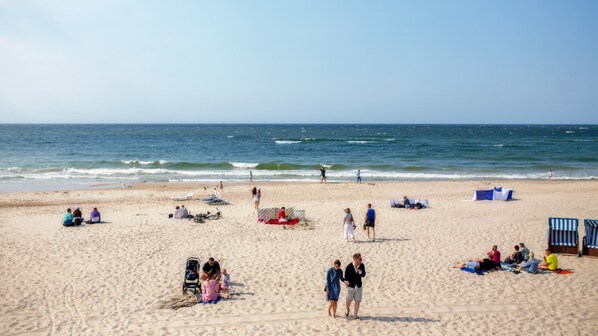 Una playa con gente, sillas y sombrillas.