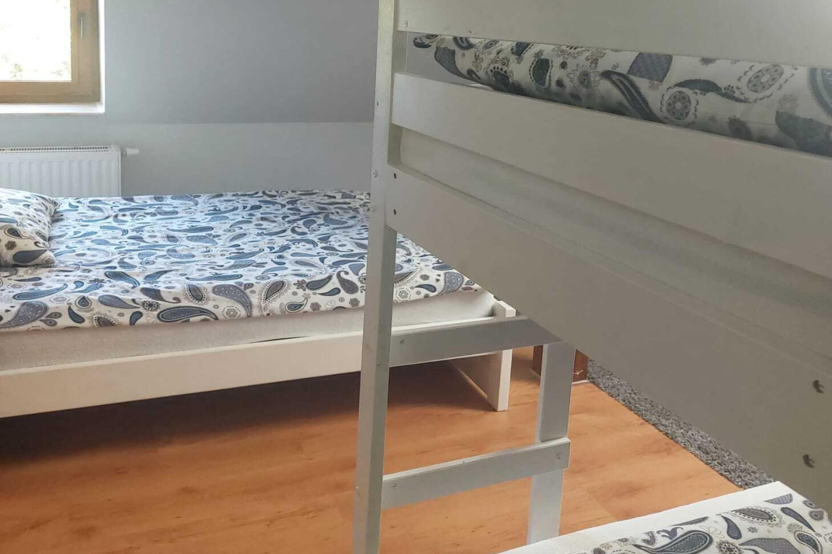 Ein Zimmer mit einem Etagenbett, einem Fenster mit Jalousien und einer Heizung.