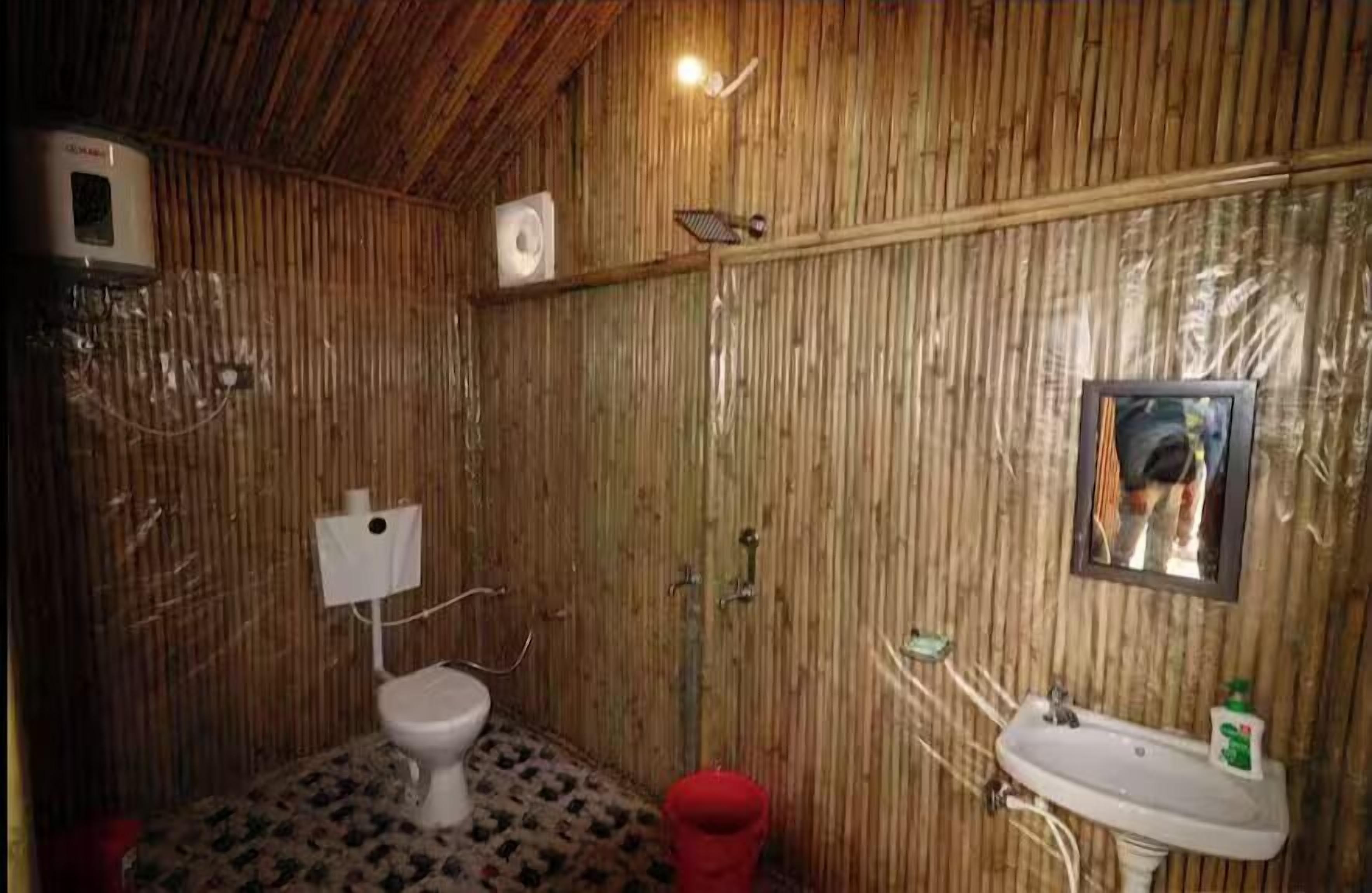 A bathroom with a toilet, sink, and mirror.