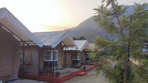 A row of tents with steps leading up to the entrance, set against a mountainous backdrop. - Shivadri Resort  (Rishikesh)