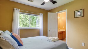 A bedroom with a bed, pillows, a window with curtains, a door leading to a bathroom, and a framed picture on the wall. - 11 Mi to Dtwn Houston: Pet-friendly Home w/ Yard! (Houston)