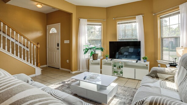 A living room with a staircase, a flat-screen TV, a coffee table, and a sofa. - 11 Mi to Dtwn Houston: Pet-friendly Home w/ Yard! (Houston)