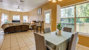 A dining area with a table set for four, a ceiling fan, and a view of the backyard through large windows. - 11 Mi to Dtwn Houston: Pet-friendly Home w/ Yard! (Houston)