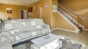 A living room with a sofa, a coffee table, a staircase, and a door leading to another room. - 11 Mi to Dtwn Houston: Pet-friendly Home w/ Yard! (Houston)