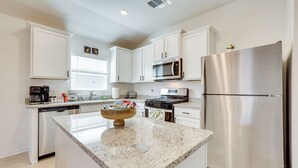 A modern kitchen with white cabinets, stainless steel appliances, and a granite countertop. - Game Room + Private Yard: Modern San Antonio Home (San Antonio)