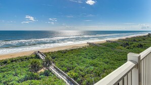 Vista costera con playa, océano y zona verde con un paseo de madera.