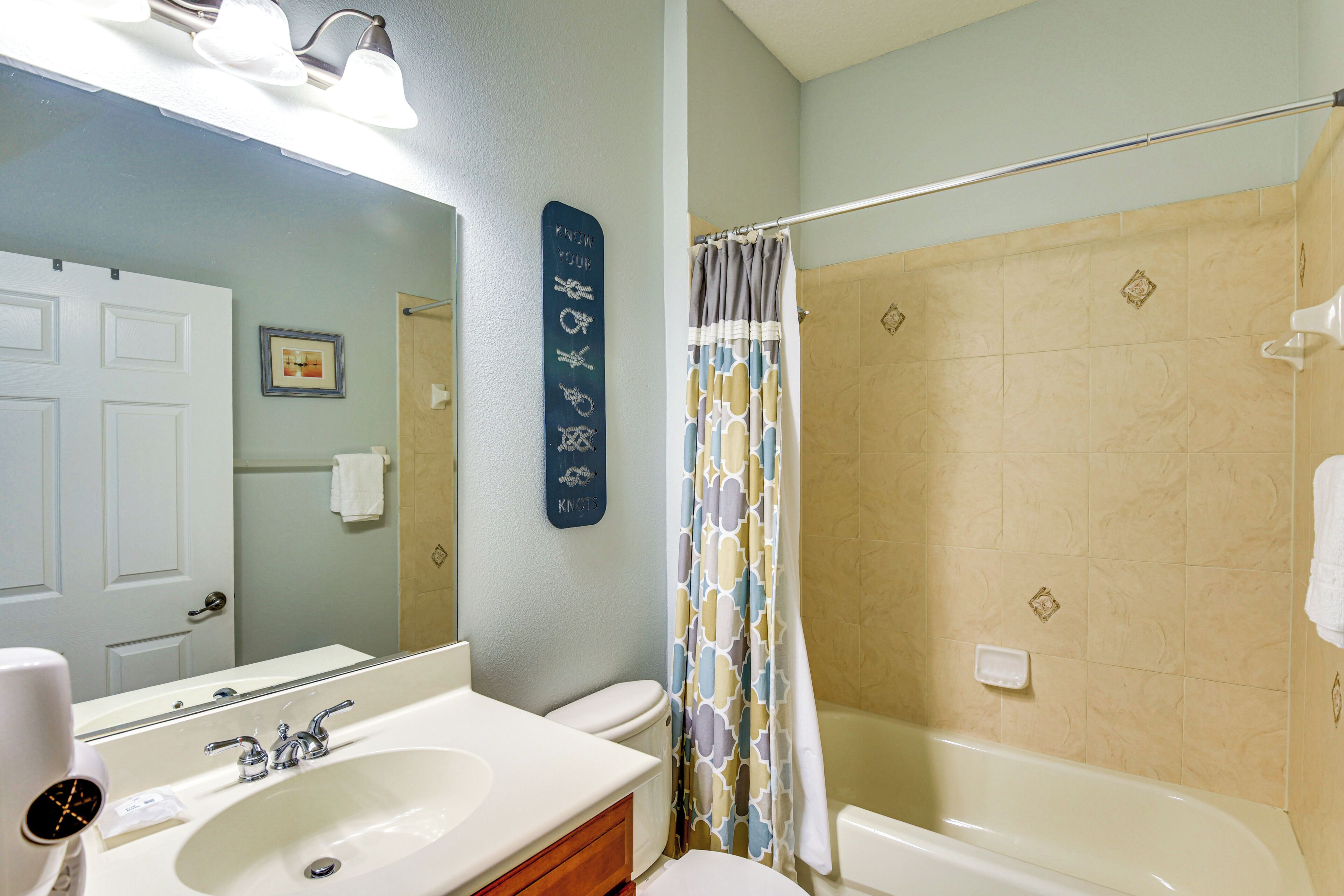 A bathroom with a sink, mirror, toilet, and shower.