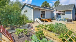 A house with a backyard garden, a patio with a table and chairs, and a slide. - Close to Everything! Quiet Retreat in Bend (Bend)