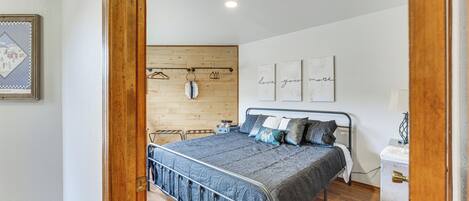 A bedroom with a bed, wooden wall paneling, a wall-mounted coat rack, and a bedside table.