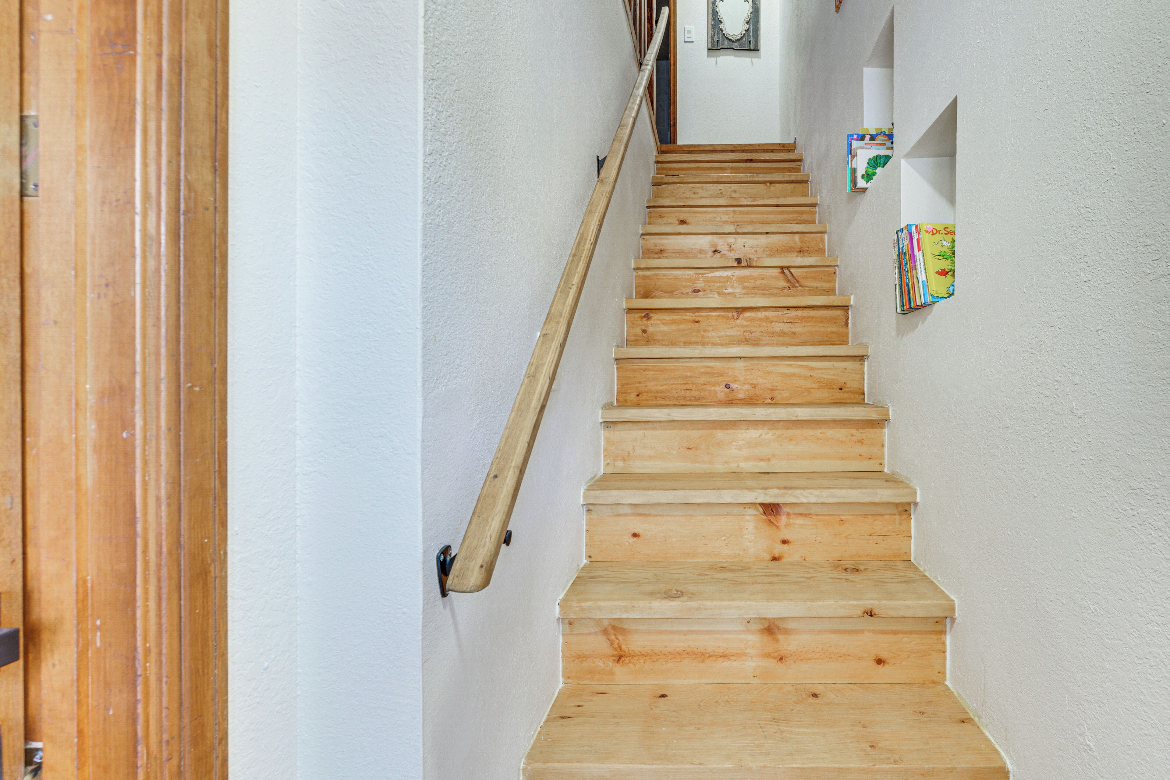 Eine Holztreppe mit Handlauf, die zu einer Zwischenebene führt.