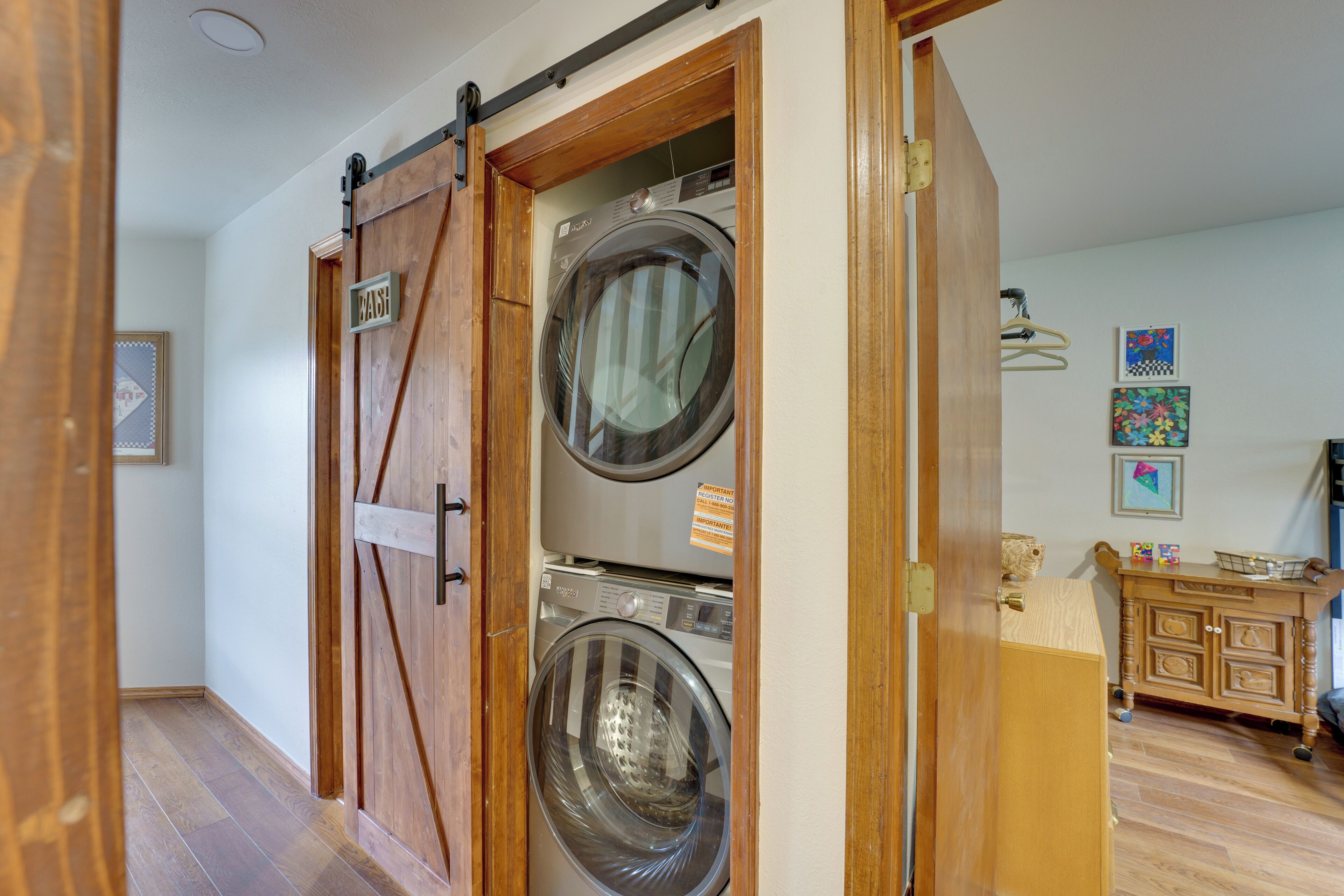 Een wasserette met twee gestapelde voorladers voor wasmachines en drogers, houten kasten en een klein tafeltje met een mand.