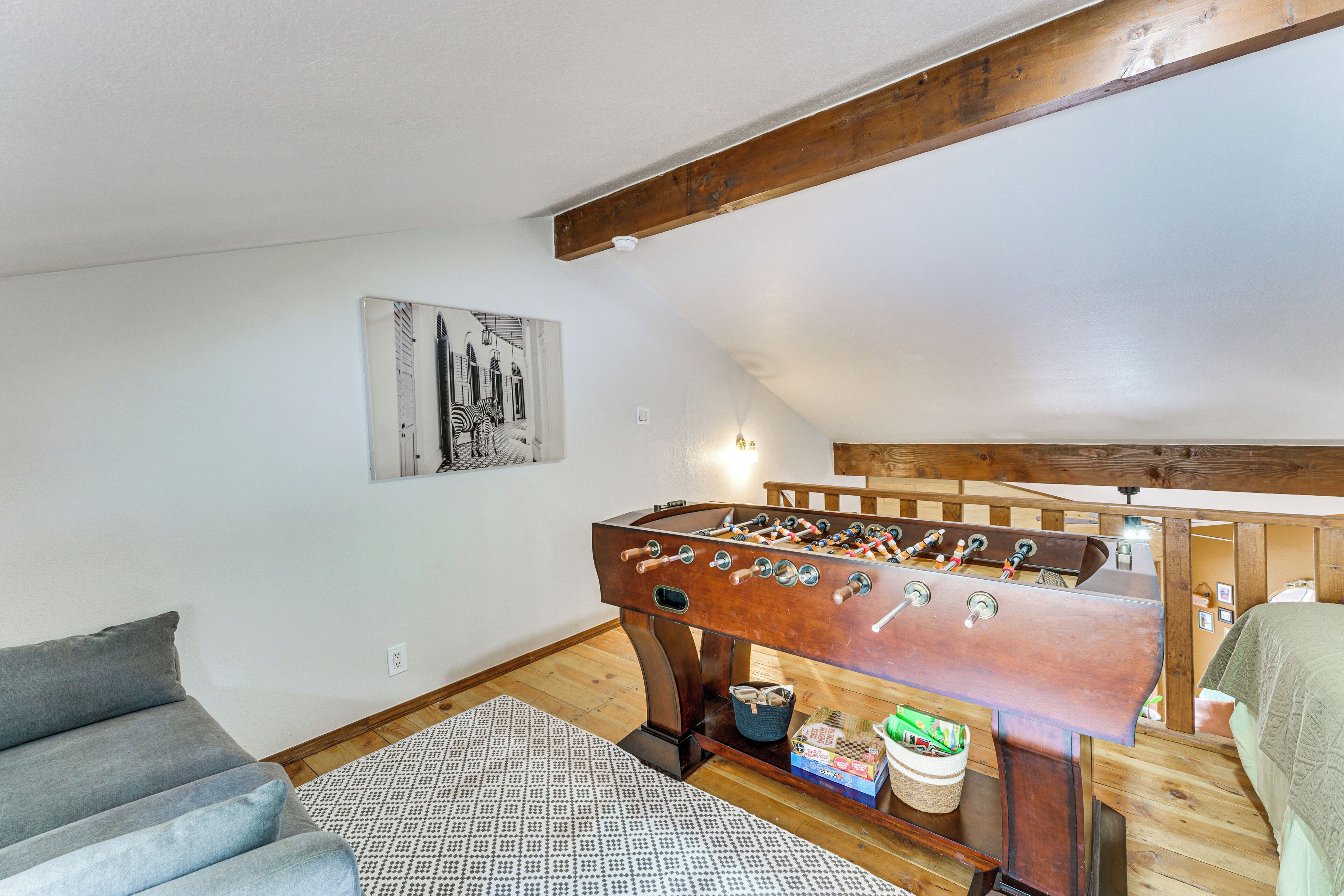 A cozy room with a foosball table, a gray sofa, and a patterned rug.