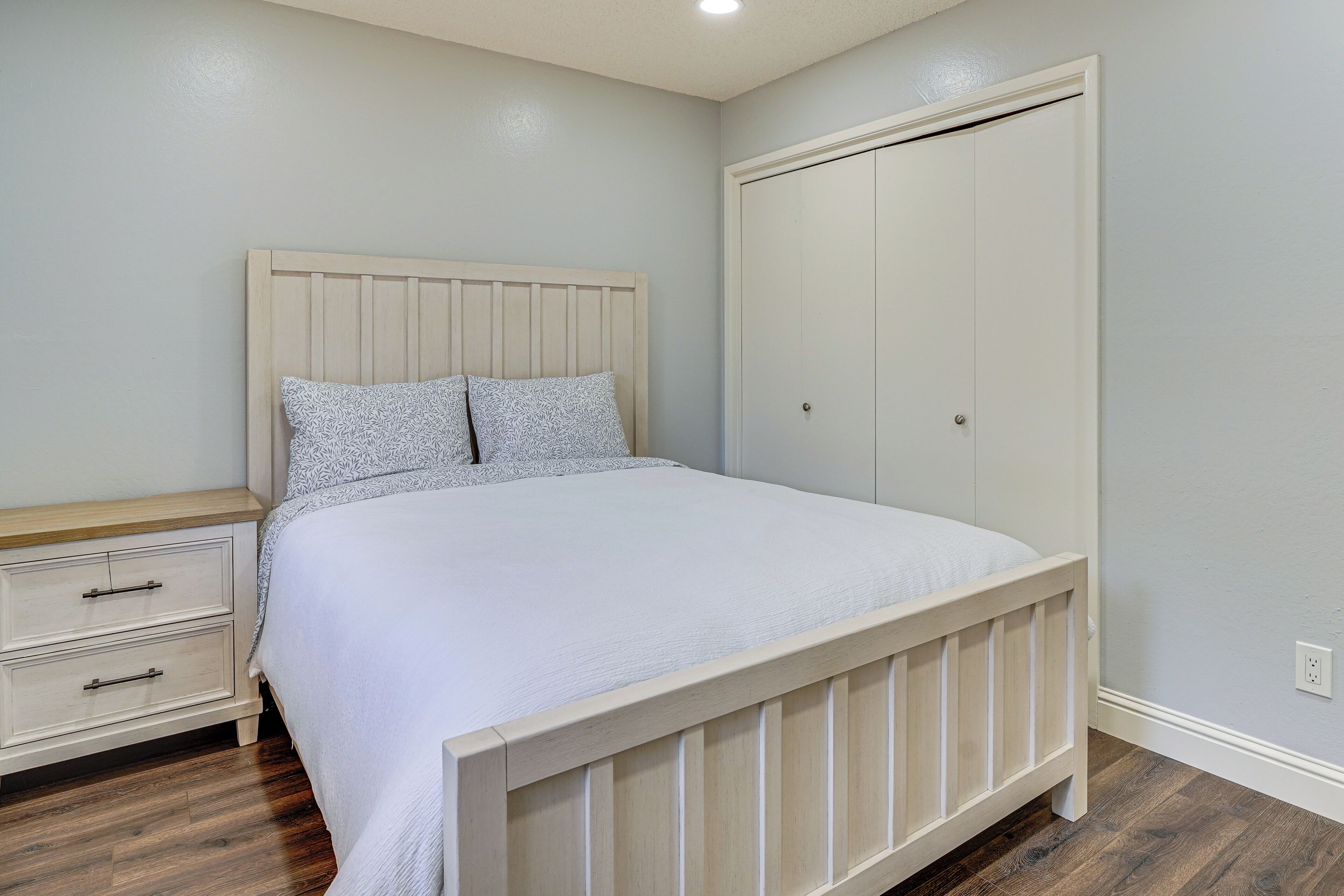 Ein Schlafzimmer mit Bett, Nachttisch, Kleiderschrank und Holzboden.