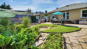 A backyard with a stone pathway, a wooden deck, and a patio area with a table and chairs. - Near Hiking, Dining & Parks! Sunny SLC Retreat (Salt Lake City)