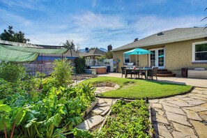 A backyard with a stone pathway, a wooden deck, and a patio area with a table and chairs. - Near Hiking, Dining & Parks! Sunny SLC Retreat (Salt Lake City)