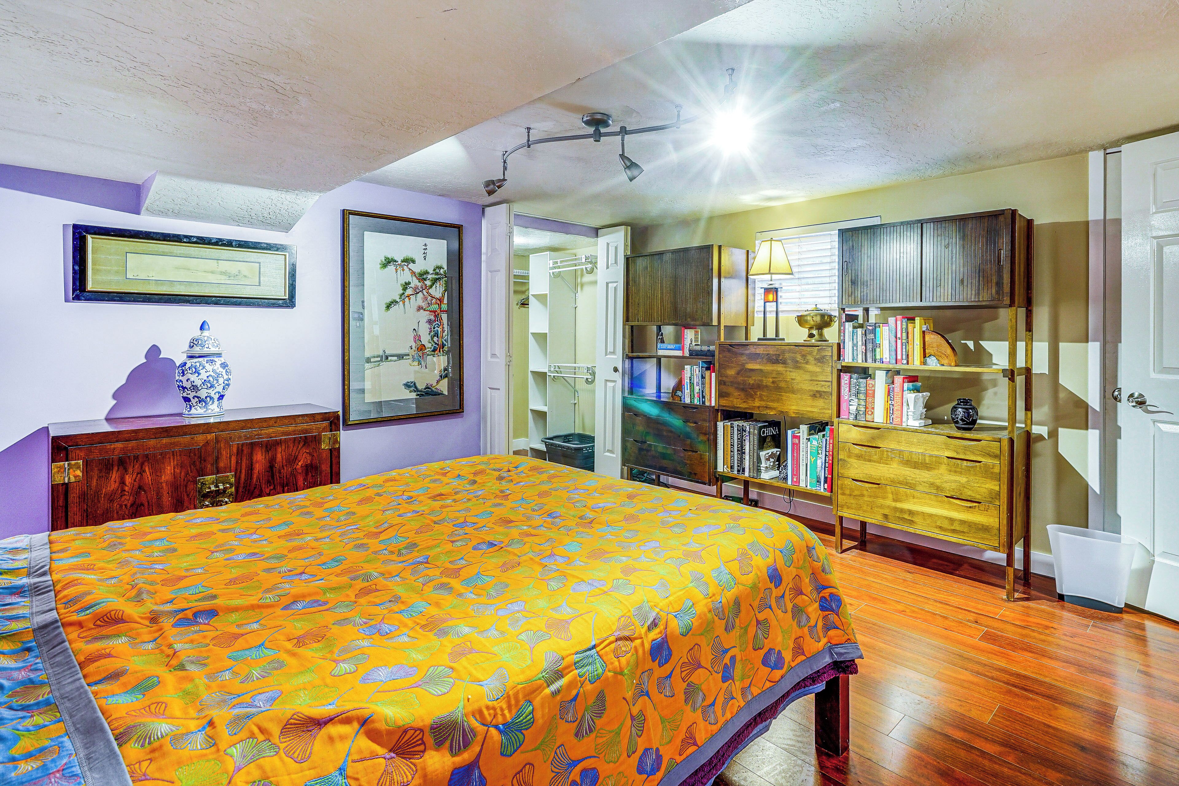 Quarto com cama, móveis de madeira, estante e porta.