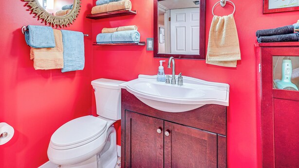 A bathroom with a red wall, a white sink, a mirror, and multiple towels. - Near Hiking, Dining & Parks! Sunny SLC Retreat (Salt Lake City)