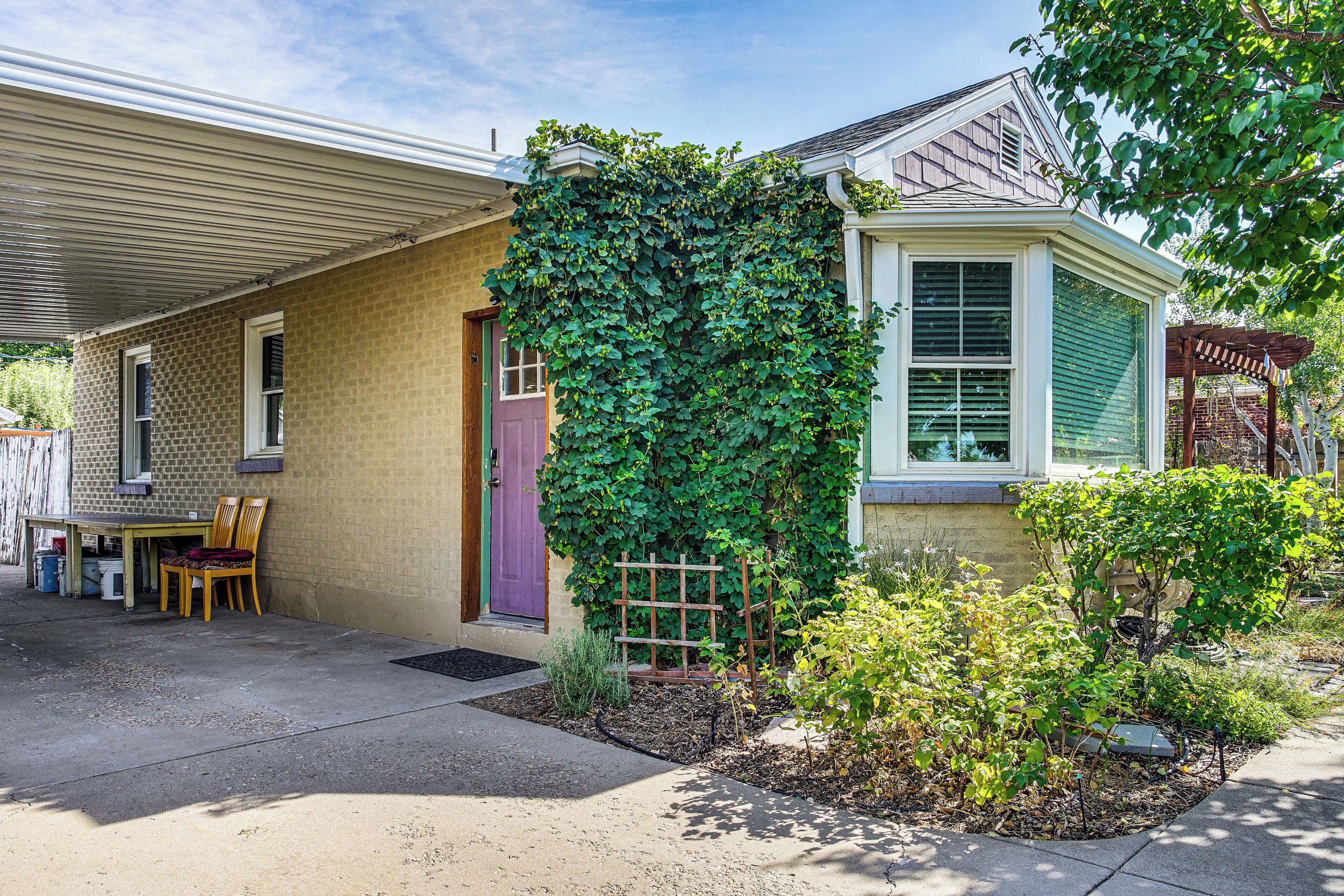 A house with a covered porch, a small garden, and a wooden table with chairs.