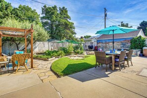 Un patio trasero con pérgola, mobiliario exterior y zona de comedor.