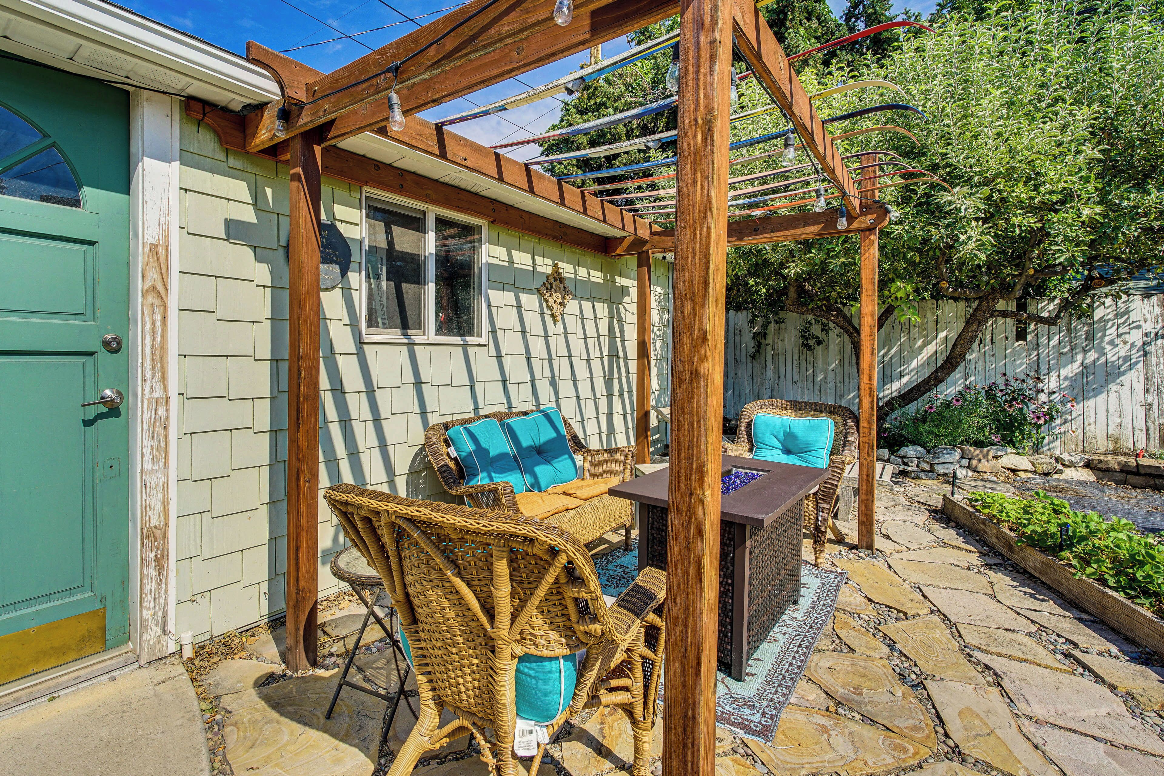 A covered patio area with wicker furniture, a table, and a hanging clothesline.