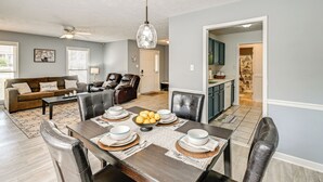 A dining area with a wooden table set for six, surrounded by leather chairs. A chandelier hangs above the table, and a ceiling fan is visible in the background. - Large Yard, Office Space: Fayetteville Family Home (Fayetteville)