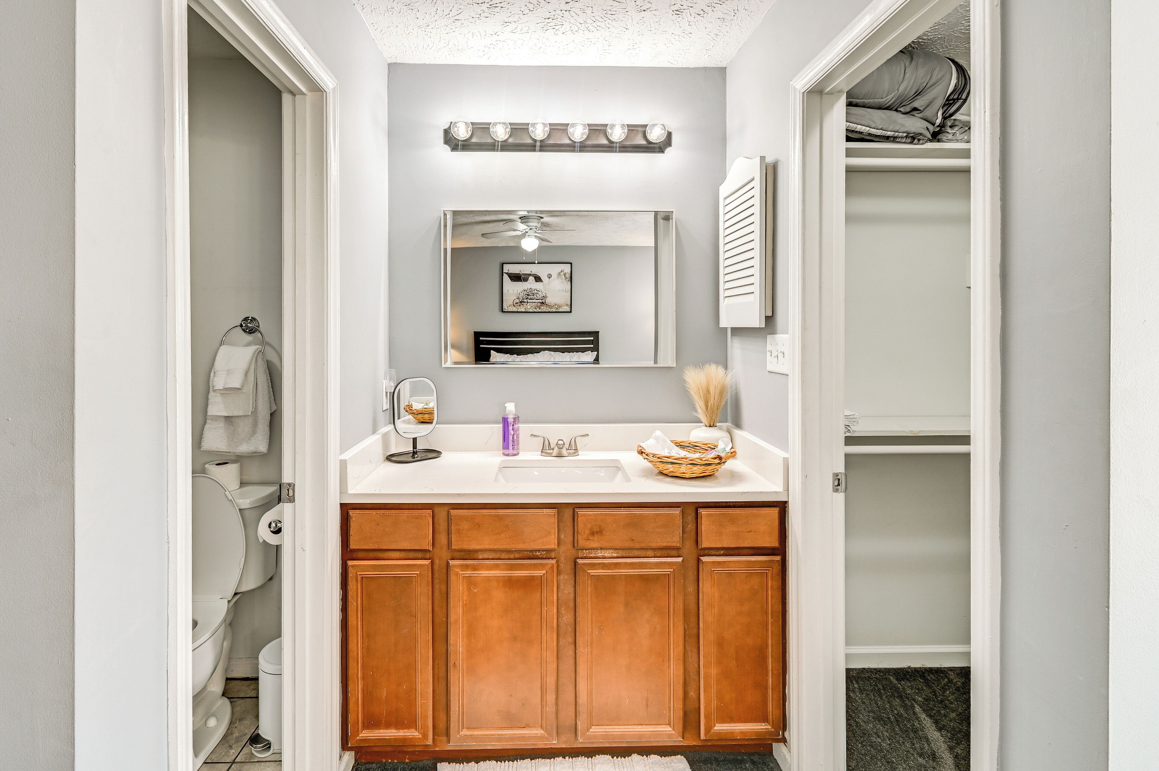A bathroom with a white vanity, wooden cabinets, a mirror, and a ceiling fan.