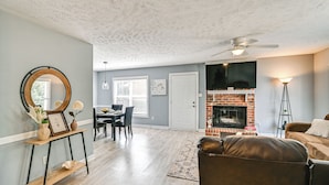 A living room with a fireplace, a dining area, and a ceiling fan. - Large Yard, Office Space: Fayetteville Family Home (Fayetteville)