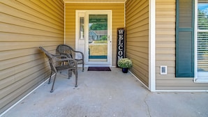 A porch with a 'WELCOME' sign, wicker chairs, and a potted plant. - Large Yard, Office Space: Fayetteville Family Home (Fayetteville)