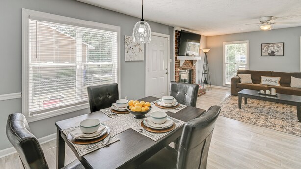A dining area with a table set for four, a fireplace, and a living room with a couch. - Large Yard, Office Space: Fayetteville Family Home (Fayetteville)