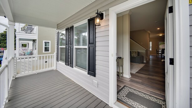 A covered porch with a white railing, a black lantern, and a door leading to a room with a wooden floor. - Walk to Beach: Group Getaway in Coastal Virginia (Norfolk)