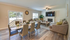 A spacious living room with a dining area, a fireplace, and a TV mounted on the wall. - Walk to Beach: Group Getaway in Coastal Virginia (Norfolk)
