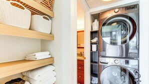 A laundry area with stacked towels, a washing machine, and shelves with baskets.