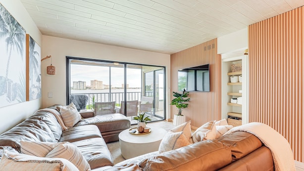 A modern living room with a large sofa set, a round coffee table, and a view of the city through large windows.