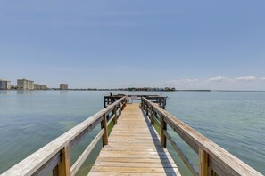 A wooden pier extending into calm water with a clear sky above.