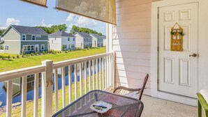A balcony with a view of houses across a body of water, a white door with a 'Bellevue' sign, and a table with a placemat.