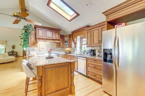 A kitchen with wooden cabinets, a stainless steel refrigerator, and a skylight.