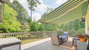 Ett trädäck med utemöbler, en pergola och utsikt över träd och en gräsmatta.
