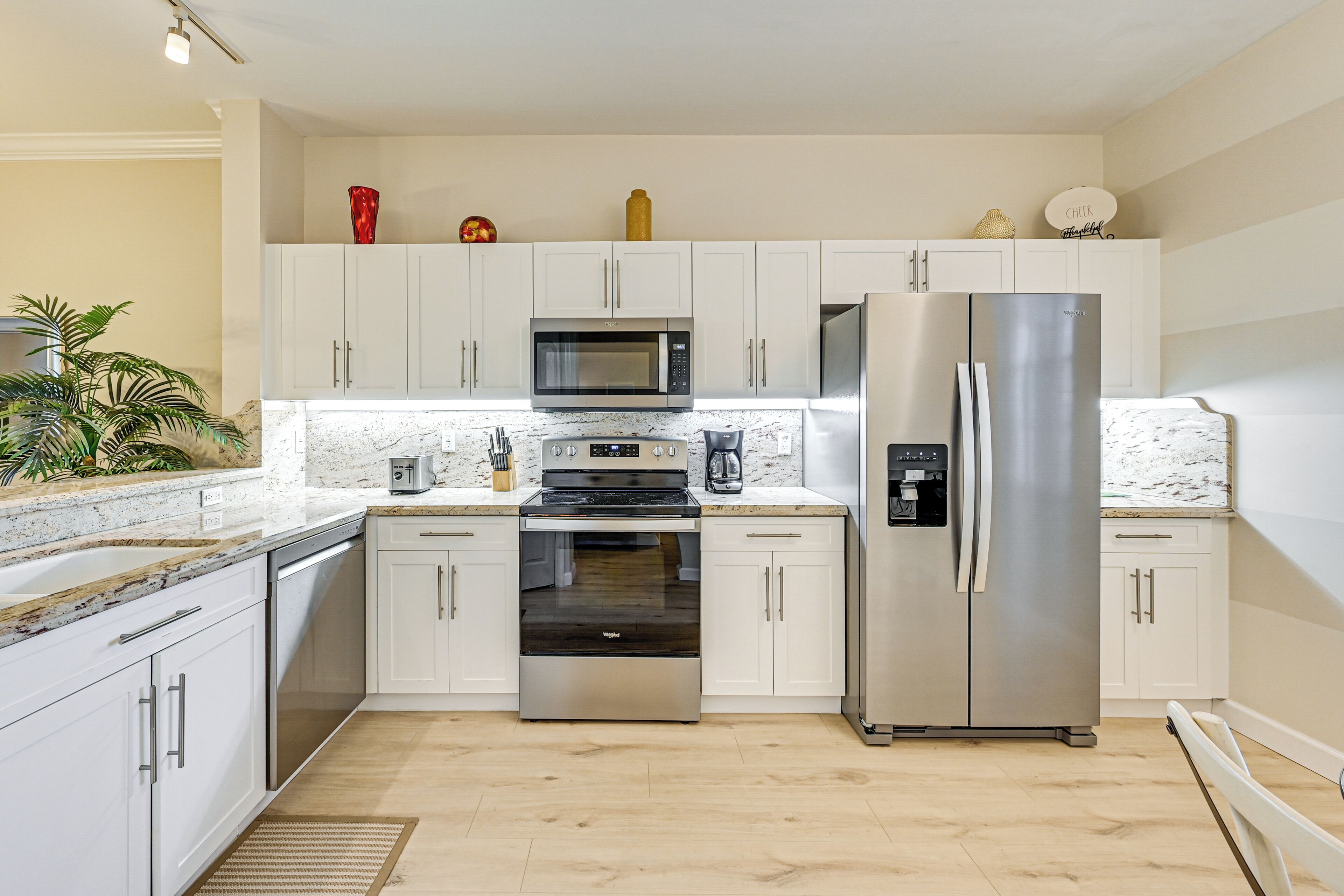 Una cocina moderna con gabinetes blancos, electrodomésticos de acero inoxidable y encimera de mármol.