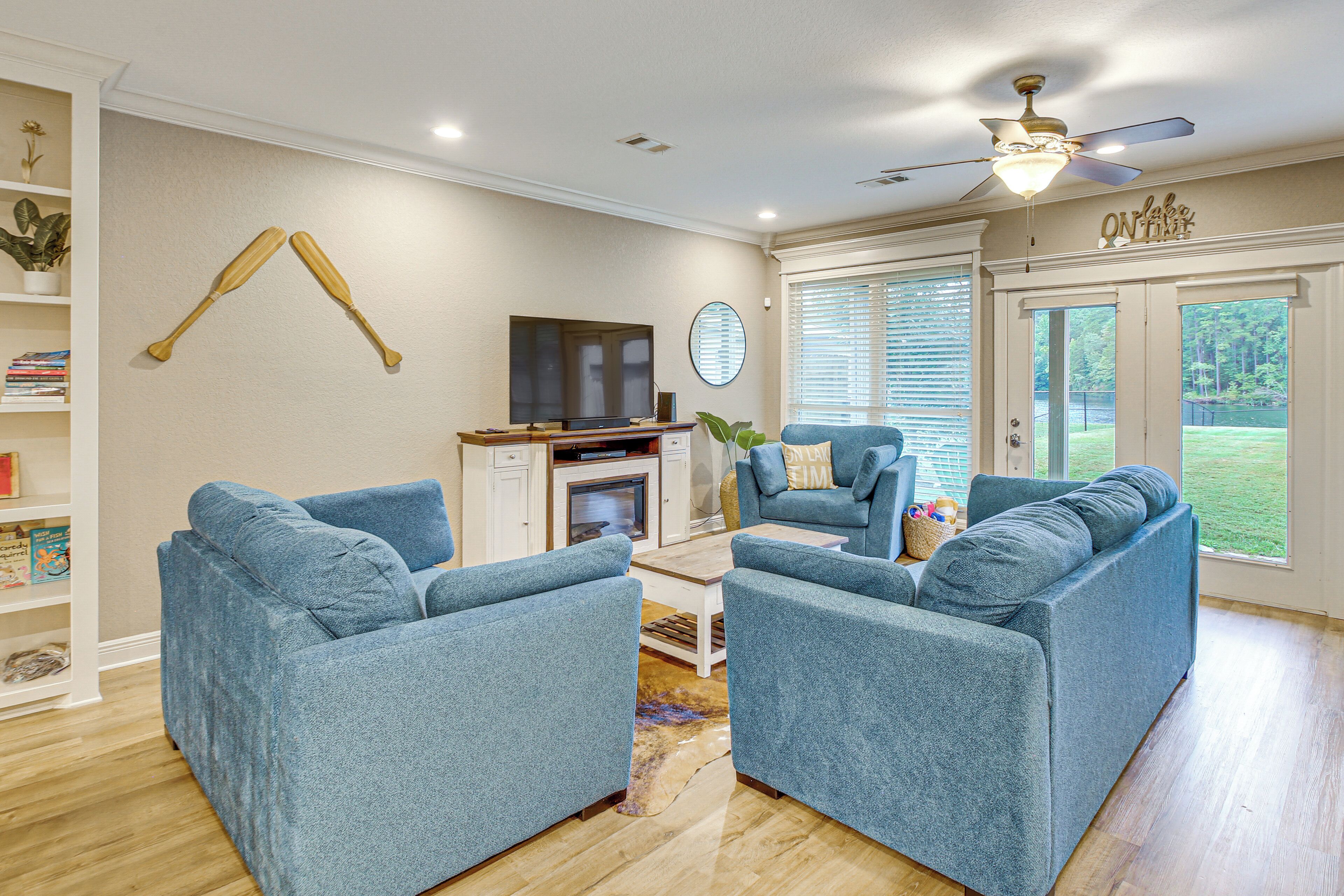 A living room with two blue armchairs, a television, and a ceiling fan.