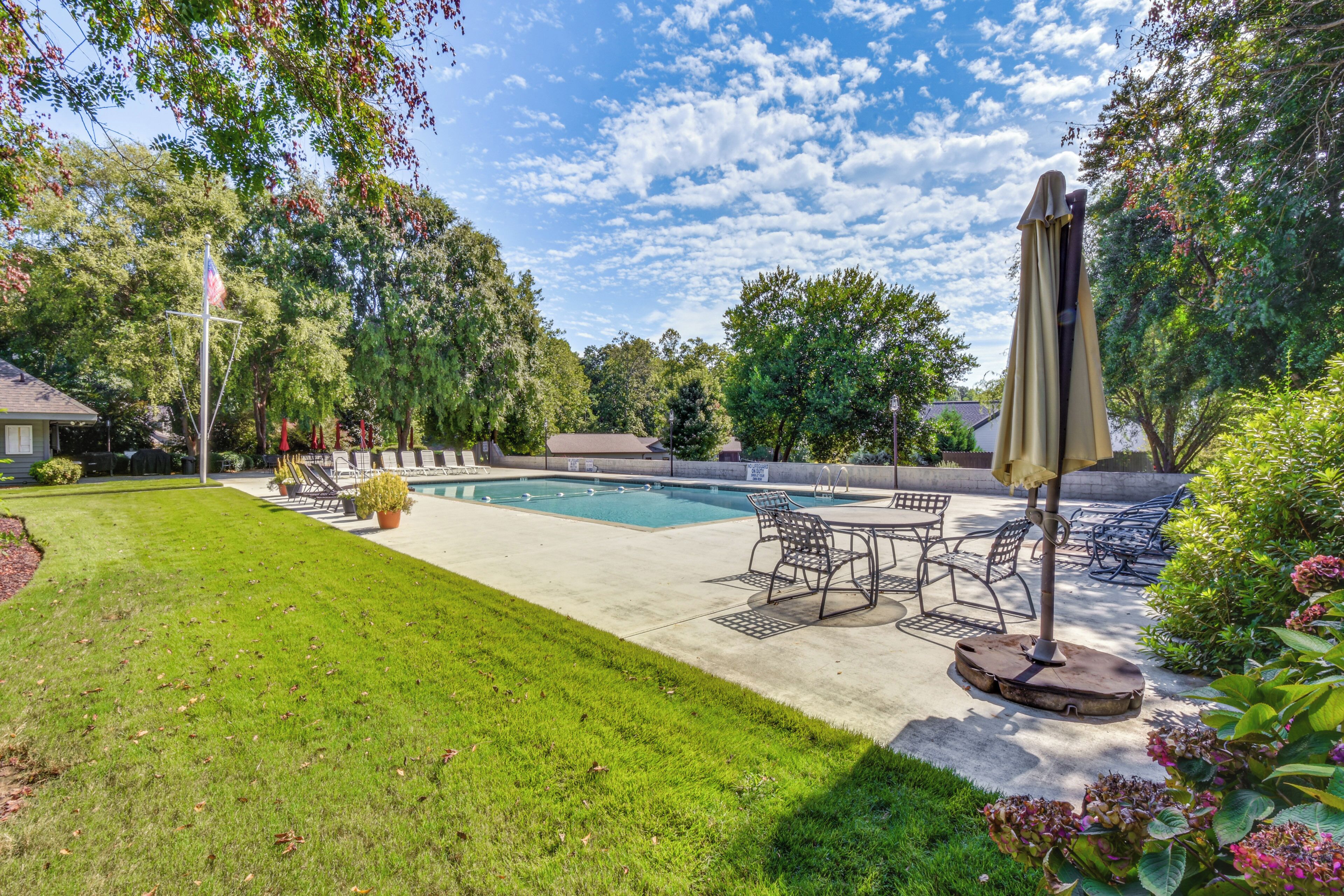 A backyard with a swimming pool, patio furniture, and a flagpole.
