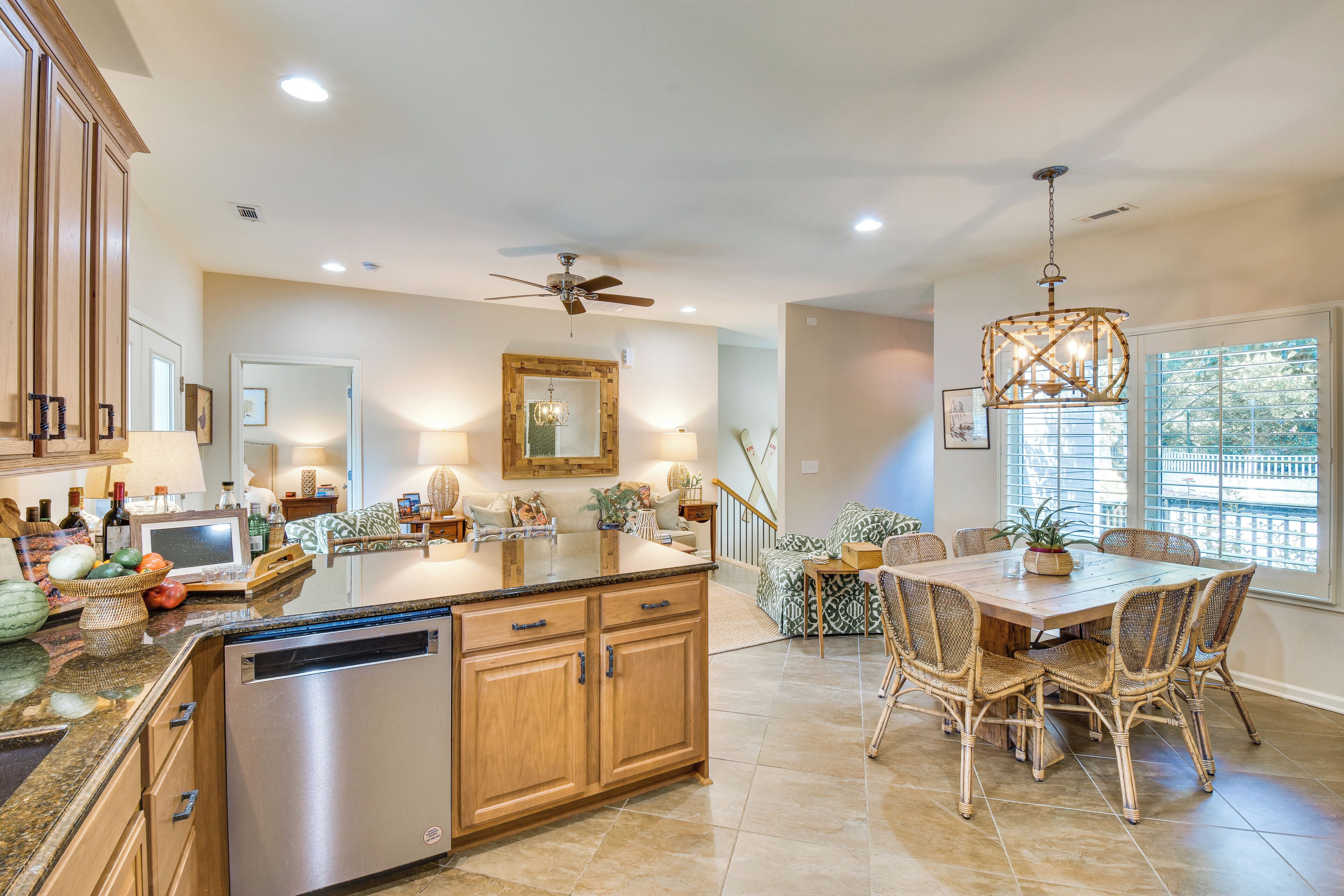 A spacious kitchen with wooden cabinets, a dishwasher, and a dining area with wicker chairs and a wooden table.