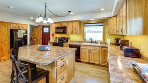 A kitchen with wooden cabinets, granite countertops, a central island, and modern appliances. - 'hayward Valley House' Black Hills Family Retreat (Keystone)