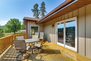 A deck with a table and chairs, a sliding glass door, and a view of the outdoors.