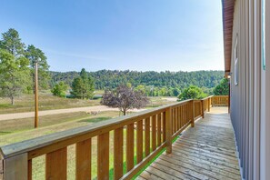 A wooden deck with a view of a forested hillside.