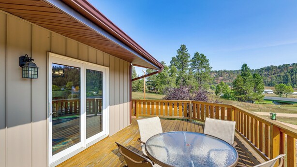 A wooden deck with a glass door leading to a covered patio area. - 'hayward Valley House' Black Hills Family Retreat (Keystone)