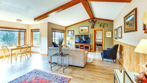 A spacious living room with wooden beams, a large TV, and a dining area with wooden furniture. - 'hayward Valley House' Black Hills Family Retreat (Keystone)