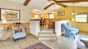 A spacious living area with a high ceiling, wooden beams, a dining area, and a kitchen with large windows. - 'hayward Valley House' Black Hills Family Retreat (Keystone)