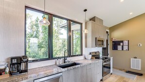 Una cocina moderna con un amplio ventanal, electrodomésticos integrados y un lavavajillas de acero inoxidable.